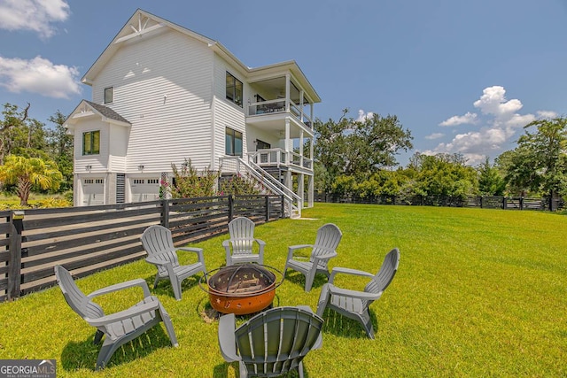 exterior space featuring a balcony, stairway, fence, an outdoor fire pit, and a yard