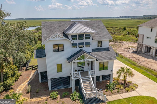 view of front of house featuring stairs, a standing seam roof, roof with shingles, and metal roof