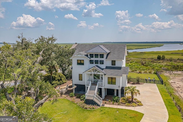 view of front of home featuring a front lawn, fence, a water view, stairs, and driveway