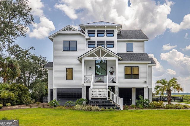 coastal home featuring stairs, a front yard, and a shingled roof