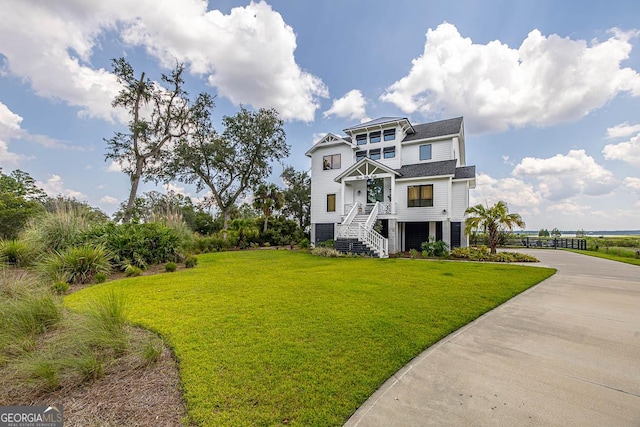 raised beach house featuring concrete driveway and a front lawn