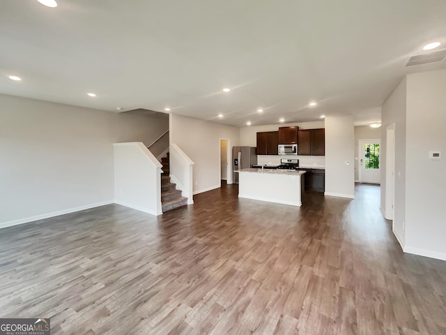 unfurnished living room with stairs, baseboards, wood finished floors, and recessed lighting