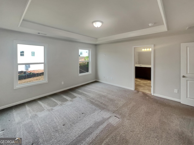 unfurnished bedroom with carpet floors, visible vents, a tray ceiling, and baseboards