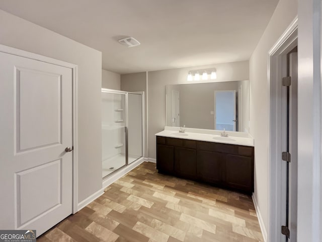 bathroom with double vanity, a shower stall, and a sink