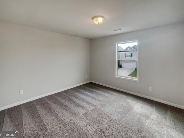 empty room featuring carpet flooring, visible vents, and baseboards