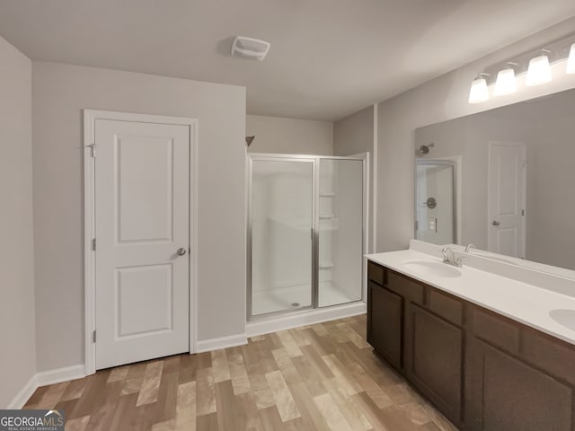 bathroom with hardwood / wood-style floors, dual bowl vanity, and an enclosed shower