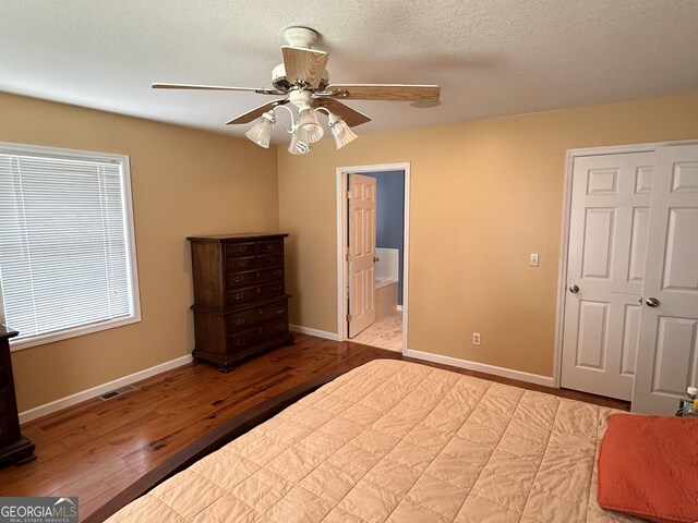 unfurnished bedroom featuring a textured ceiling, light hardwood / wood-style flooring, ceiling fan, and connected bathroom