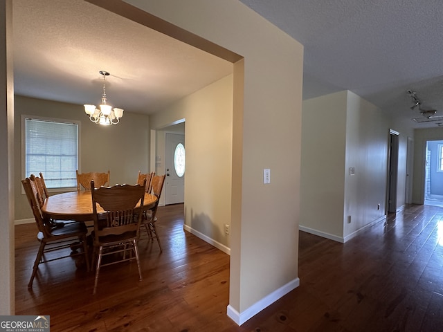 dining space with dark hardwood / wood-style flooring, a notable chandelier, a textured ceiling, and track lighting