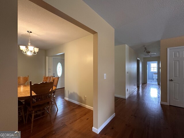 dining area featuring dark hardwood / wood-style flooring, a textured ceiling, and an inviting chandelier