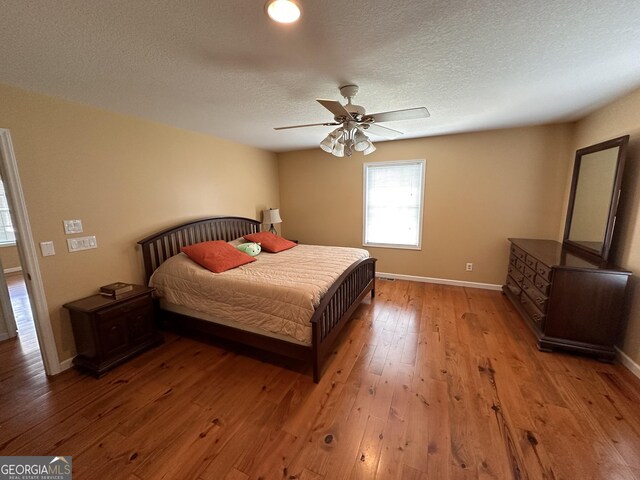 bedroom with a textured ceiling, ceiling fan, and hardwood / wood-style floors