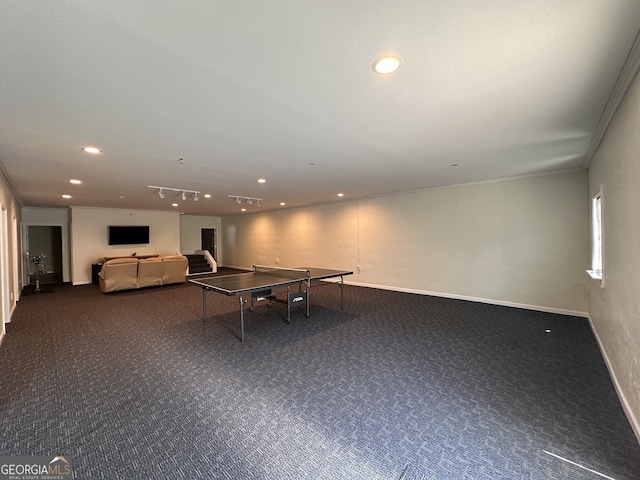 rec room featuring rail lighting, dark colored carpet, and ornamental molding