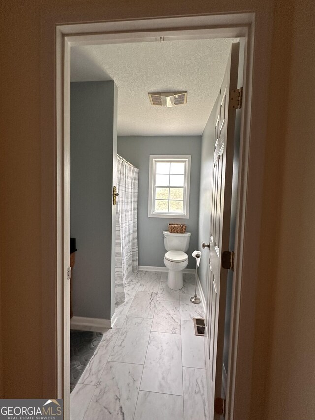 bathroom with toilet, a textured ceiling, and tile patterned floors