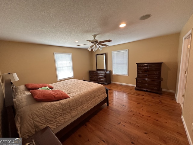 bedroom with a textured ceiling, ceiling fan, and hardwood / wood-style floors