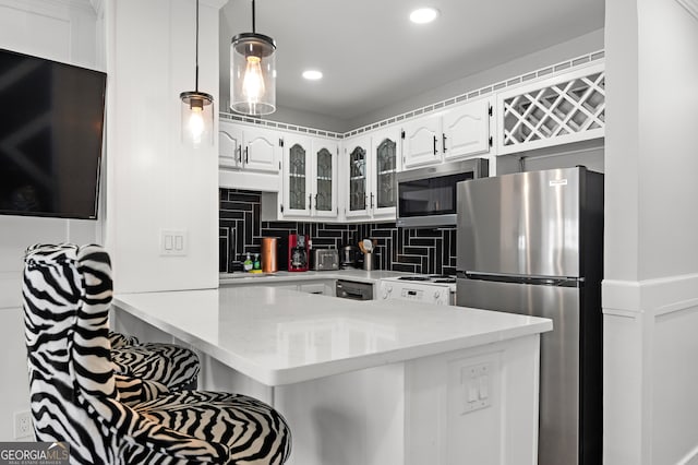 kitchen featuring backsplash, pendant lighting, white cabinets, kitchen peninsula, and stainless steel appliances