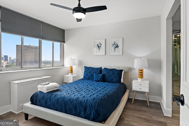 bedroom with ceiling fan, a view of city, baseboards, and dark wood-style flooring