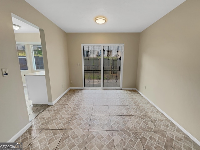 unfurnished room with light tile patterned floors, plenty of natural light, and baseboards