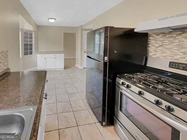 kitchen with tasteful backsplash, dark stone counters, under cabinet range hood, stainless steel range with gas cooktop, and white cabinetry