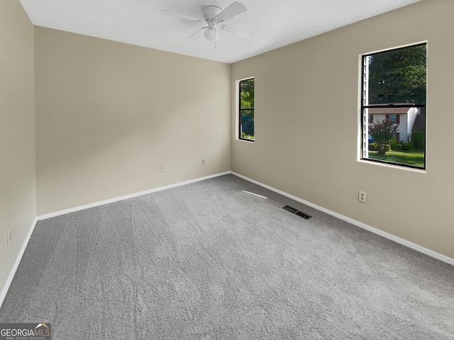 carpeted empty room featuring a ceiling fan, visible vents, and baseboards