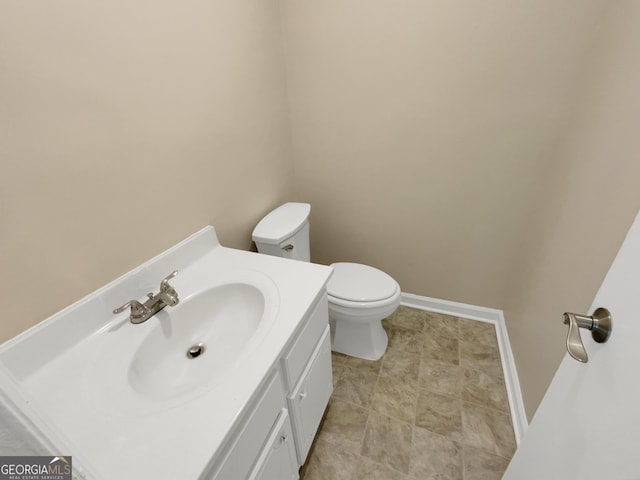 half bath with toilet, vanity, and baseboards