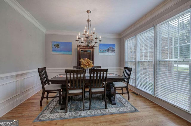 dining room with crown molding, light hardwood / wood-style floors, and a chandelier