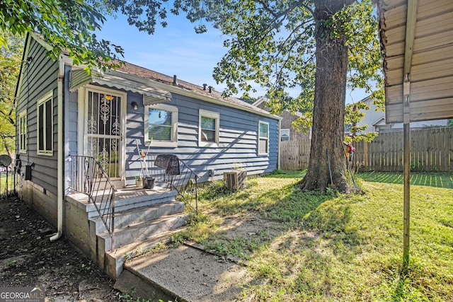 view of front of home with a front lawn and central AC