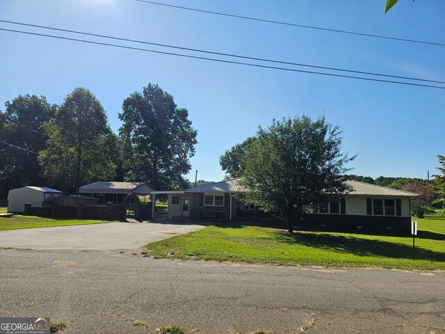 ranch-style home with concrete driveway, a front lawn, and an attached carport