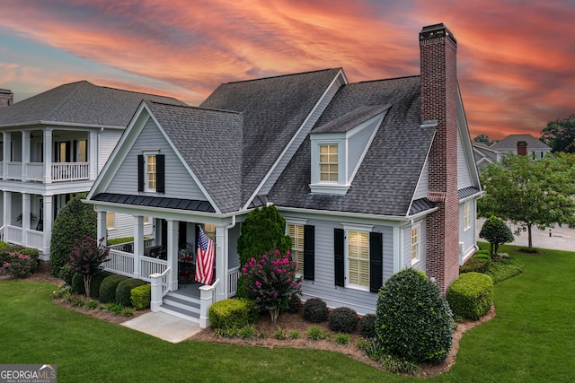 view of front of property featuring a balcony, a lawn, and covered porch