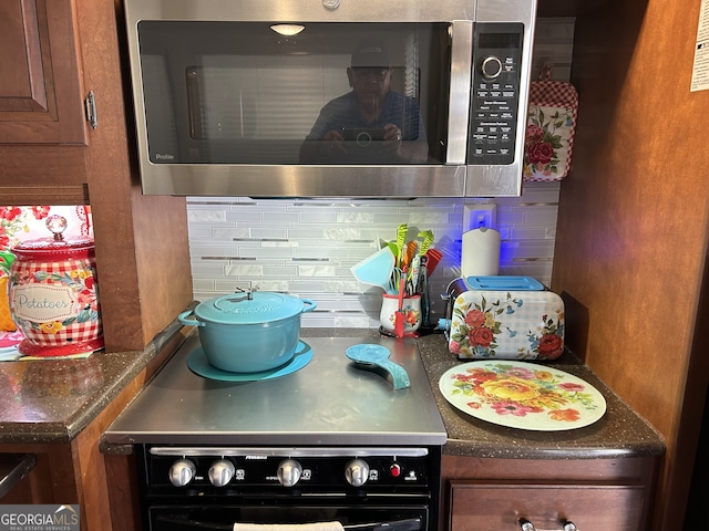 details featuring decorative backsplash and black range oven