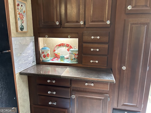 details featuring decorative backsplash and black fridge