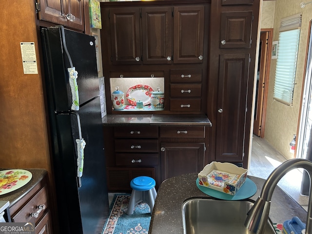 kitchen with black refrigerator, dark brown cabinetry, and sink