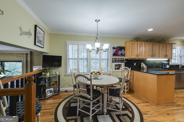 dining area with crown molding, a chandelier, and light wood-type flooring