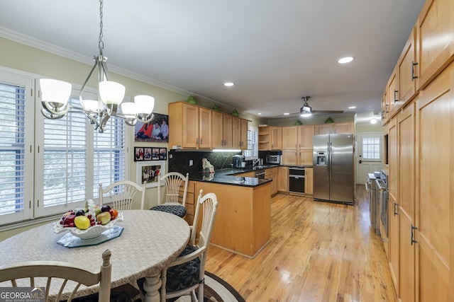 kitchen with stainless steel appliances, tasteful backsplash, light wood-type flooring, ceiling fan with notable chandelier, and kitchen peninsula