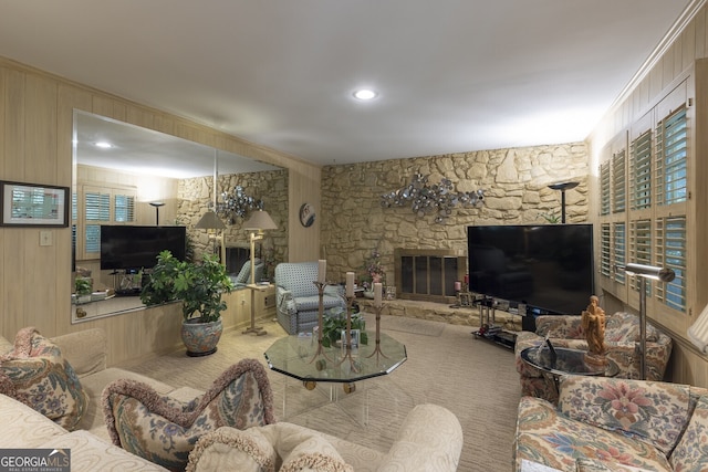 living room with a fireplace, carpet flooring, wooden walls, and a notable chandelier