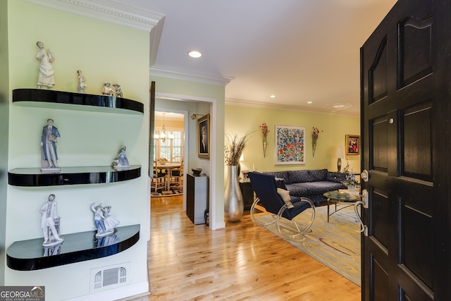 living room featuring an inviting chandelier, light hardwood / wood-style flooring, and ornamental molding