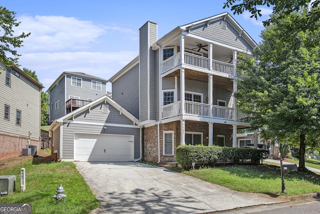 view of front of house featuring central air condition unit, a balcony, a garage, ceiling fan, and a front yard