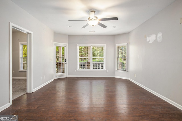 spare room featuring a healthy amount of sunlight, ceiling fan, and dark hardwood / wood-style floors