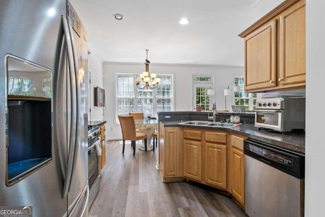 kitchen featuring sink, hanging light fixtures, a notable chandelier, wood-type flooring, and stainless steel appliances