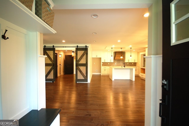 interior space with a barn door, dark wood-type flooring, and sink