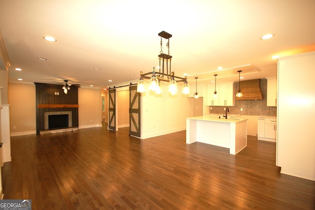 kitchen featuring white cabinetry, pendant lighting, custom exhaust hood, and a barn door