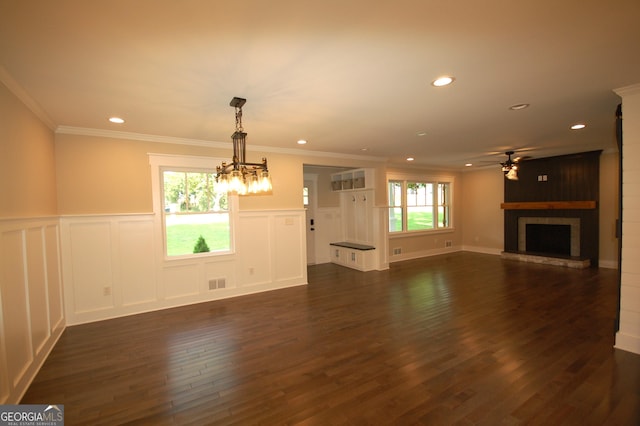 unfurnished living room featuring crown molding, a large fireplace, dark hardwood / wood-style floors, and ceiling fan with notable chandelier