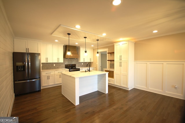 kitchen featuring white cabinetry, decorative light fixtures, custom range hood, a kitchen island with sink, and black appliances