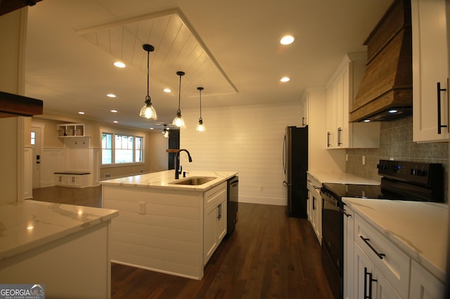 kitchen featuring white cabinetry, sink, black appliances, and a center island with sink