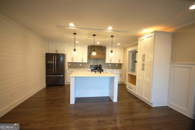 kitchen featuring white cabinetry, premium range hood, black fridge, and pendant lighting