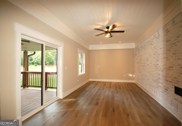 spare room featuring crown molding, dark wood-type flooring, ceiling fan, and brick wall