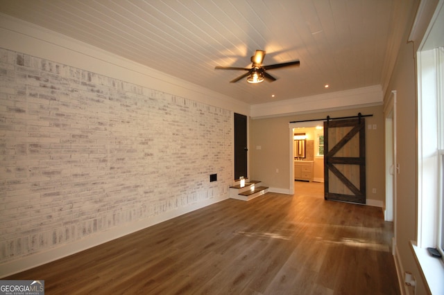 empty room with brick wall, ornamental molding, ceiling fan, a barn door, and dark wood-type flooring