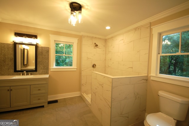 bathroom with tiled shower, ornamental molding, toilet, and vanity