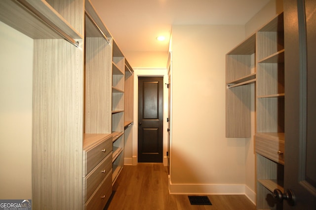 walk in closet with dark wood-type flooring