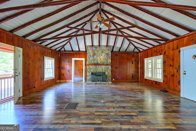 unfurnished living room featuring a fireplace, wood walls, beamed ceiling, and hardwood / wood-style flooring