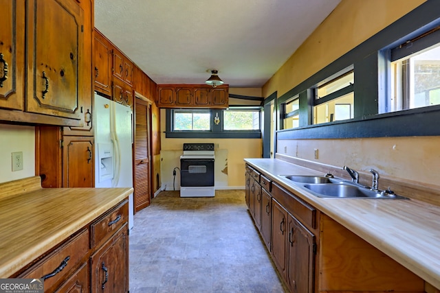 kitchen with brown cabinets, range with electric stovetop, light countertops, a sink, and white fridge with ice dispenser