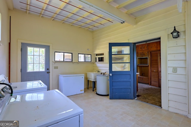 washroom with sink, wood walls, light tile patterned flooring, and washer and clothes dryer